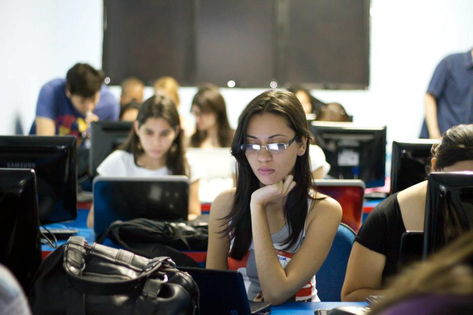 Foto da Mariana com óculos de grau e diversos monitores